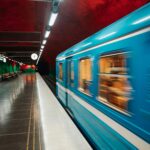 A vibrant blue train speeds through Solna Centrum station in Stockholm, Sweden.