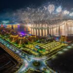 Aerial view of a vibrant fireworks display over Al Marjan Island, Ras al Khaimah, UAE at night.