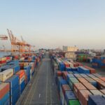 A bustling port scene with colorful cargo containers at sunrise. Ideal for logistics concepts.