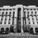 Monochrome image of a large, ornate building with arches and intricate details.