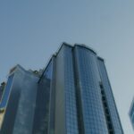 Low angle view of modern glass skyscrapers against a clear blue sky.